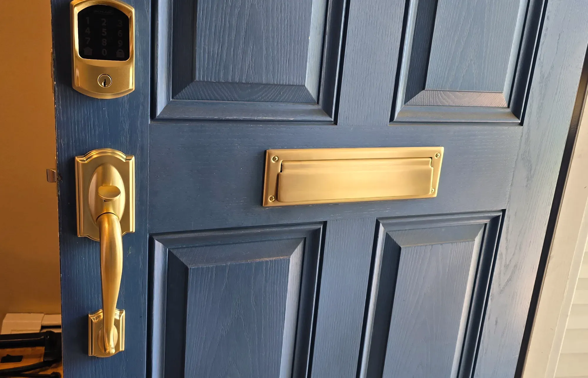 Brass keypad deadbolt, handleset and mail slot on a navy blue front door