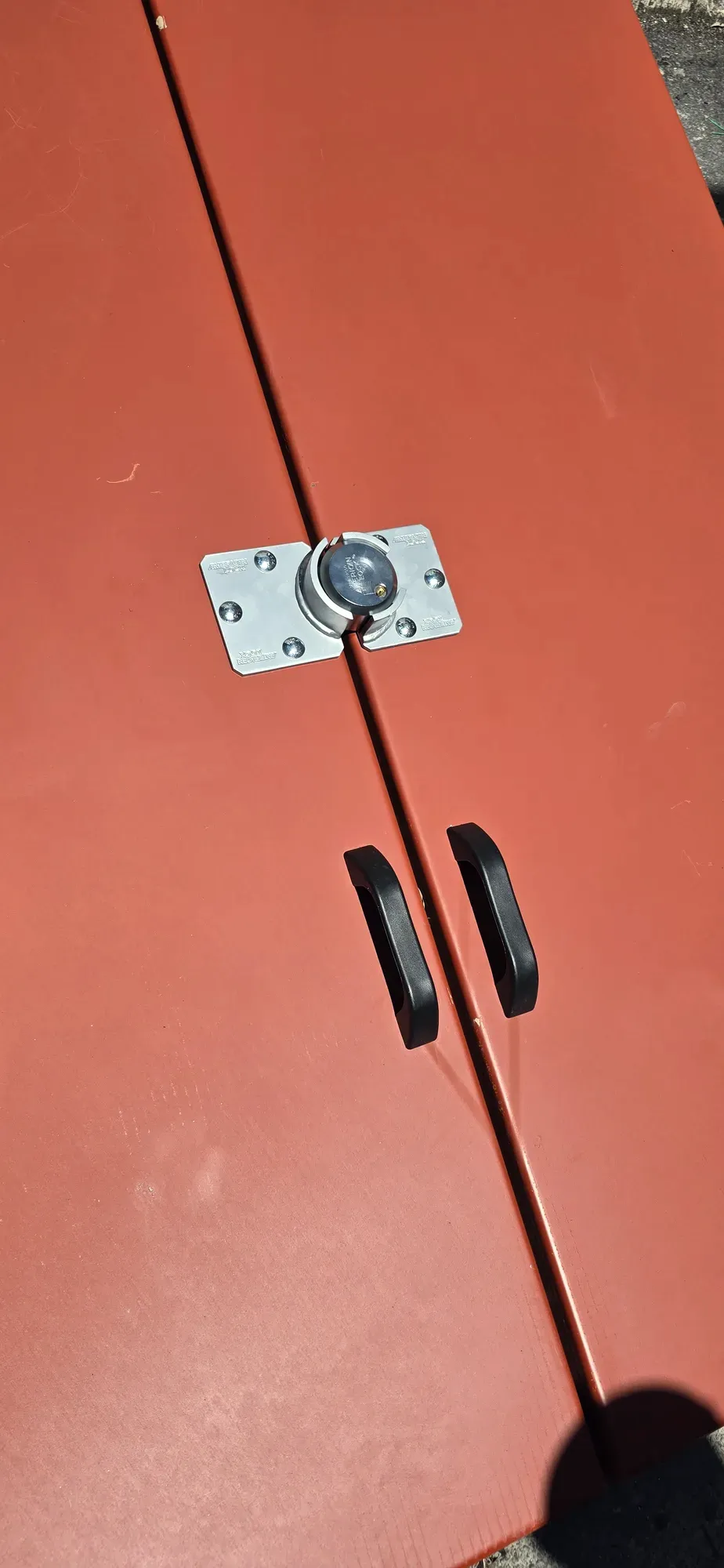 Surface-mounted hasp and laminated padlock on red steel double doors