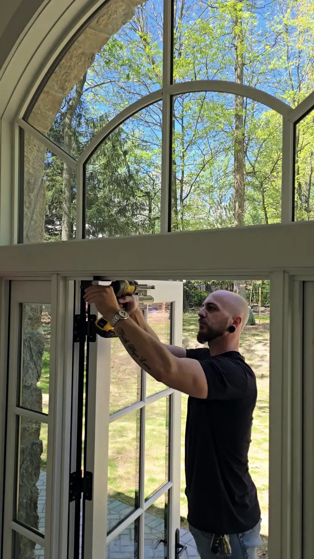 Christopher installing a hinge on a French door beneath an arched transom