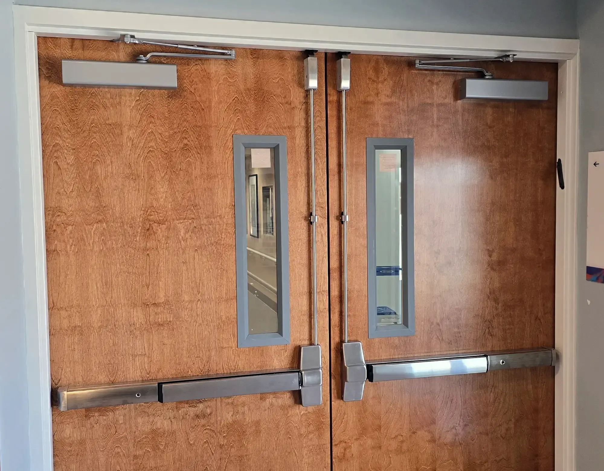 Vertical-rod panic bars and overhead closers on wood commercial double doors