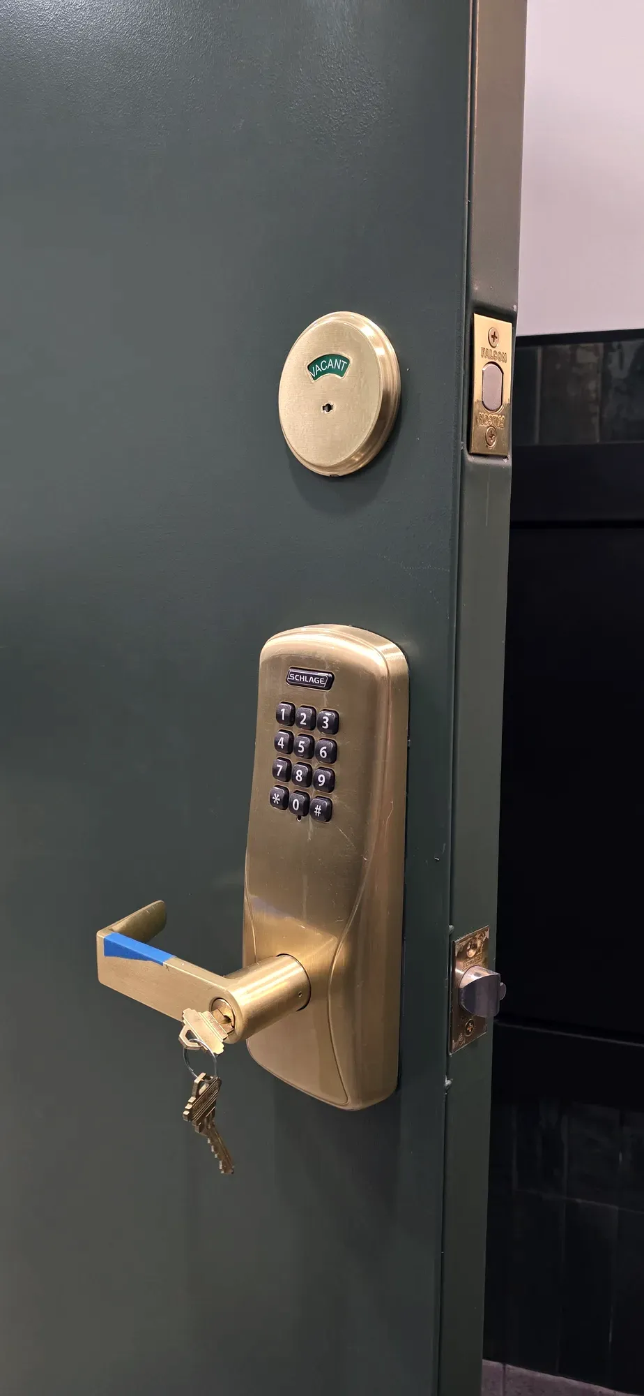 Brass keypad lever lock and deadbolt on a green interior door